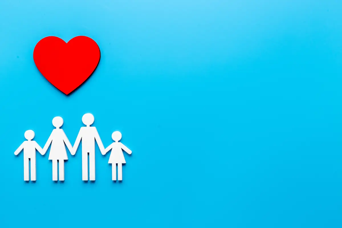 A paper cut-out family beside a red heart, representing household health coverage.
